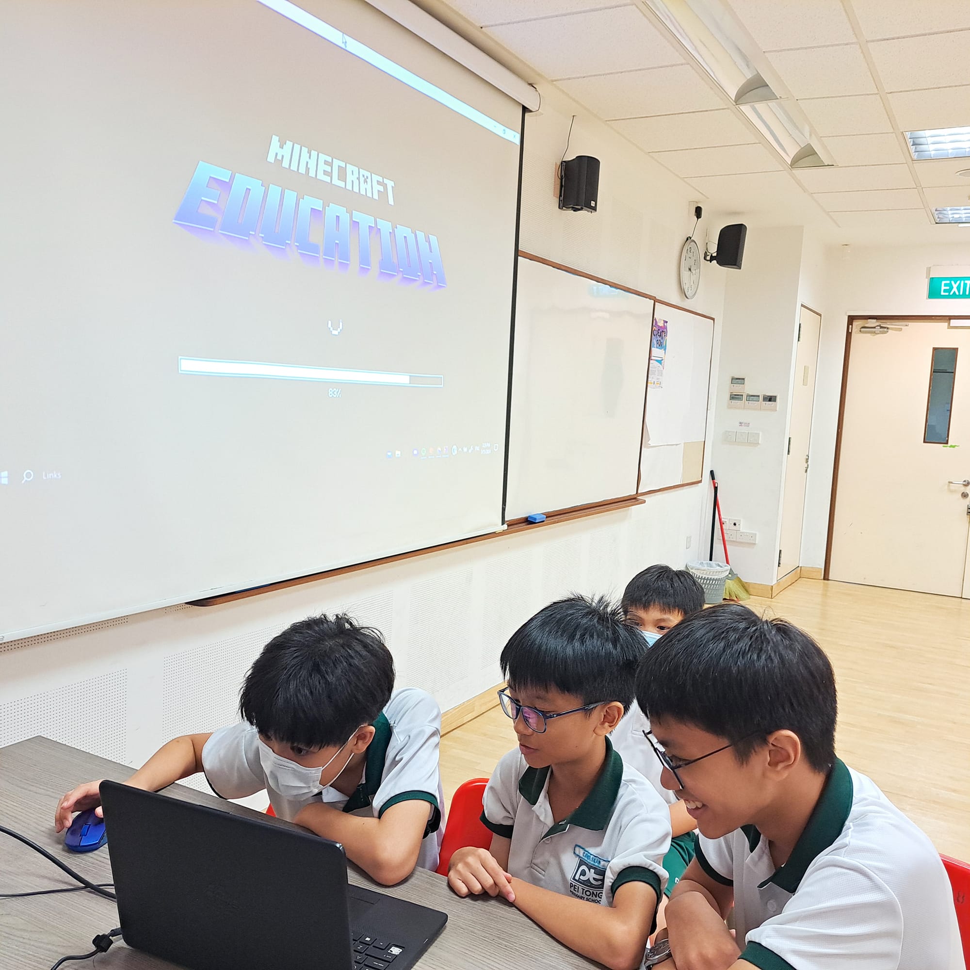 Students collaborate around a laptop while using Minecraft Education to solve challenges and develop digital literacy and problem-solving skills.